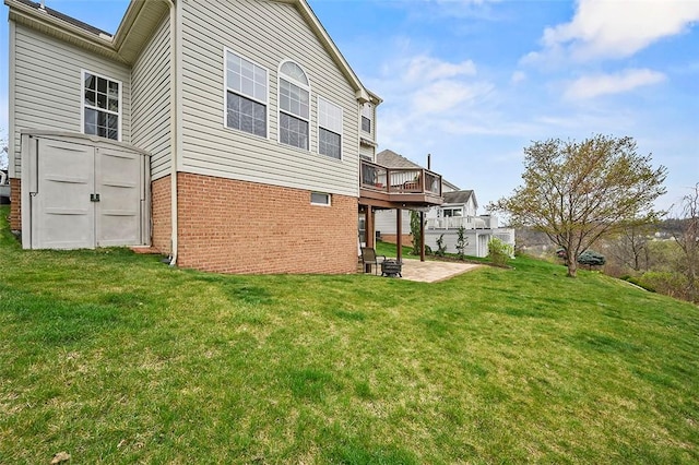 rear view of property with brick siding, a deck, a shed, a patio, and a yard