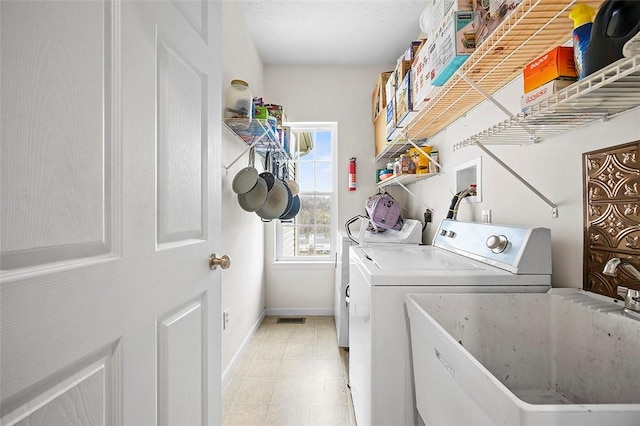 washroom with laundry area, visible vents, baseboards, washer and clothes dryer, and a sink