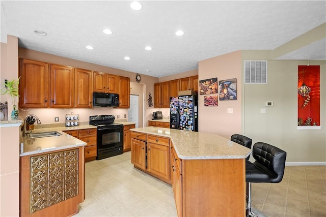 kitchen featuring visible vents, a kitchen island, recessed lighting, a sink, and black appliances