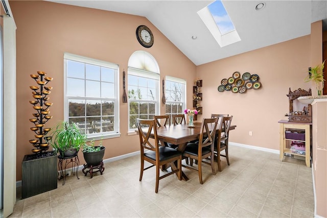 dining area featuring a skylight, baseboards, and high vaulted ceiling