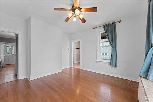 empty room with hardwood / wood-style floors, baseboards, a healthy amount of sunlight, and a ceiling fan