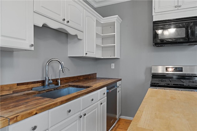 kitchen with white cabinets, butcher block countertops, a sink, and stainless steel appliances