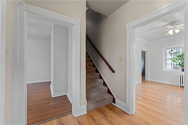 stairway with baseboards, wood finished floors, radiator heating unit, and a ceiling fan