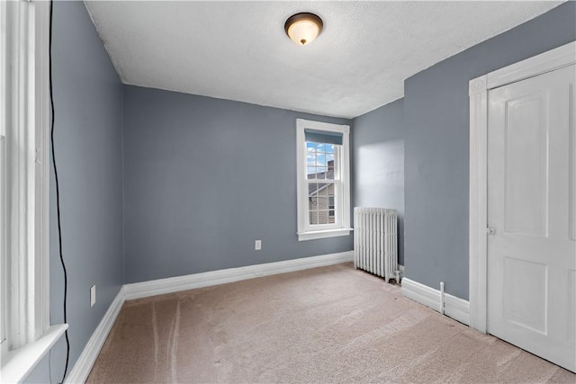 unfurnished bedroom with baseboards, carpet floors, a textured ceiling, and radiator