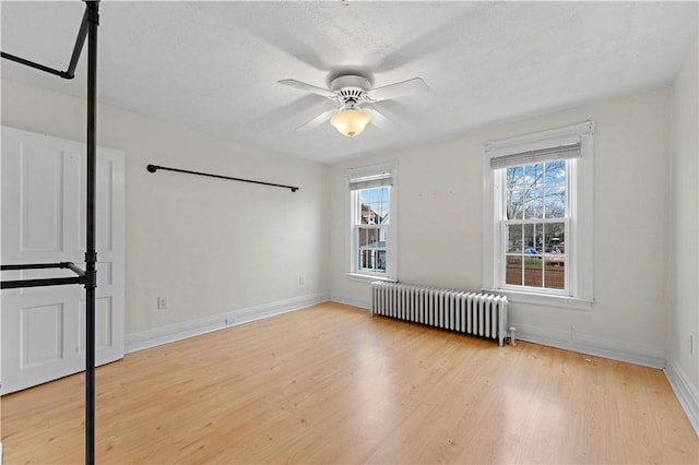 spare room featuring baseboards, ceiling fan, wood finished floors, and radiator