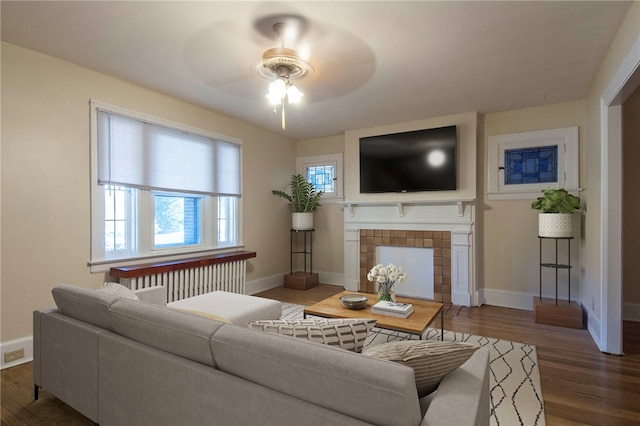 7447 Schoyer Ave, Swissvale, PA 15218 - living room with wood finished floors, radiator heating unit, a tiled fireplace, and a ceiling fan