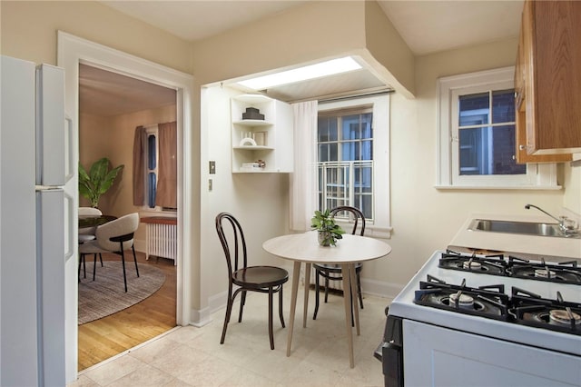 7447 Schoyer Ave, Swissvale, PA 15218 - kitchen featuring radiator heating unit, a sink, baseboards, and white appliances