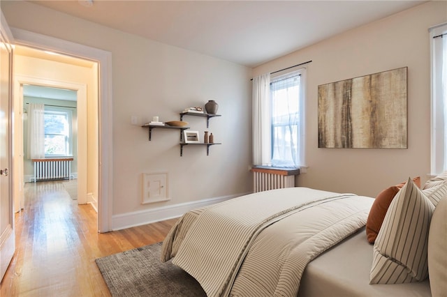 7447 Schoyer Ave, Swissvale, PA 15218 - bedroom with radiator, multiple windows, light wood-style flooring, and baseboards