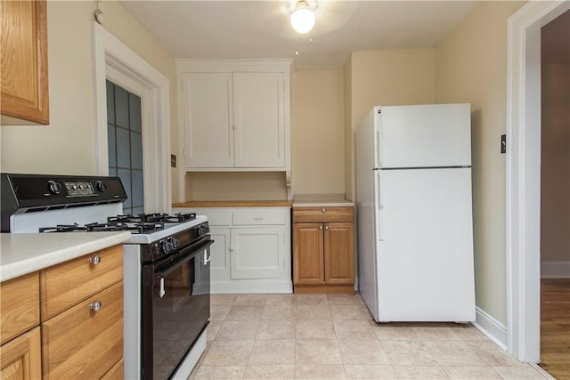 7447 Schoyer Ave, Swissvale, PA 15218 - kitchen with light countertops, gas stove, white cabinets, and freestanding refrigerator