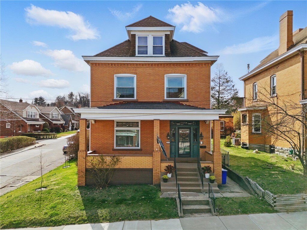 traditional style home featuring a front yard, brick siding, and roof with shingles