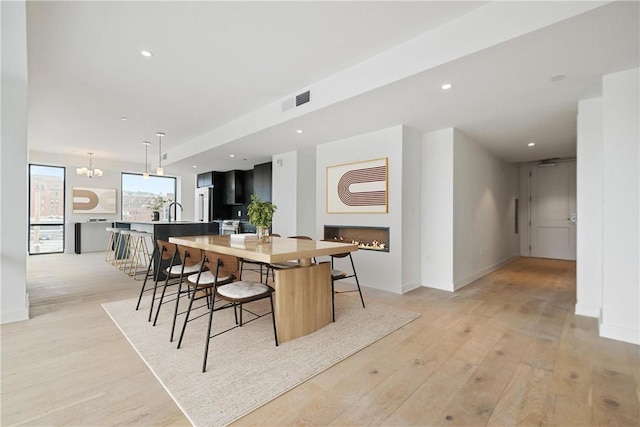 dining room featuring light wood-style floors, recessed lighting, visible vents, and a fireplace