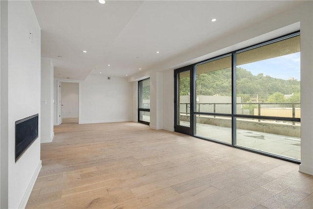 unfurnished living room featuring light wood finished floors, plenty of natural light, and recessed lighting