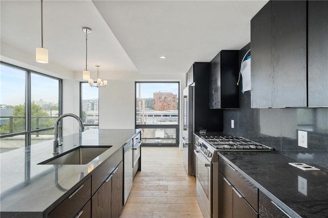 kitchen featuring a city view, light wood-type flooring, a sink, stainless steel appliances, and a notable chandelier