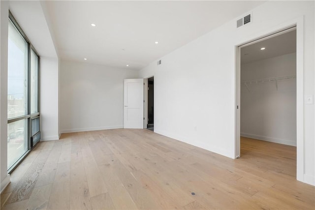 empty room featuring recessed lighting, visible vents, light wood-type flooring, and baseboards