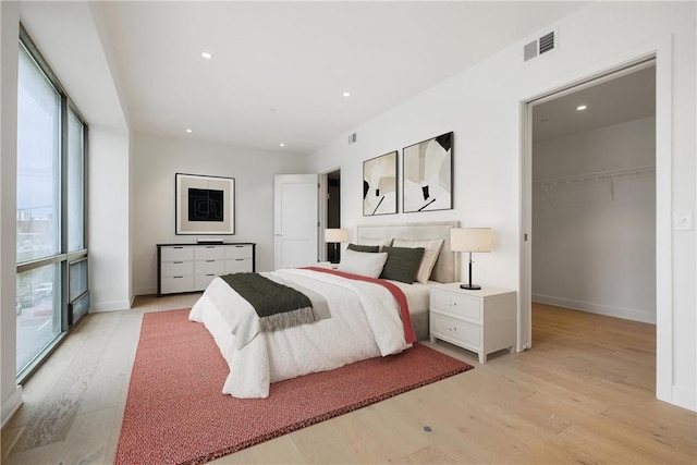 bedroom featuring a spacious closet, visible vents, light wood-style flooring, and recessed lighting