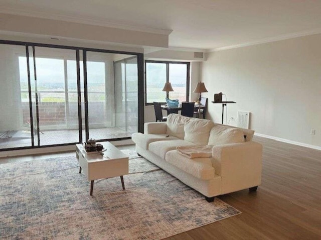 living area with crown molding, visible vents, wood finished floors, and baseboards