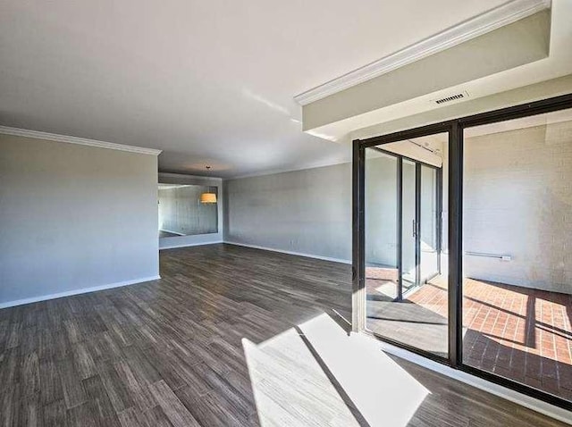 empty room featuring baseboards, visible vents, ornamental molding, and wood finished floors