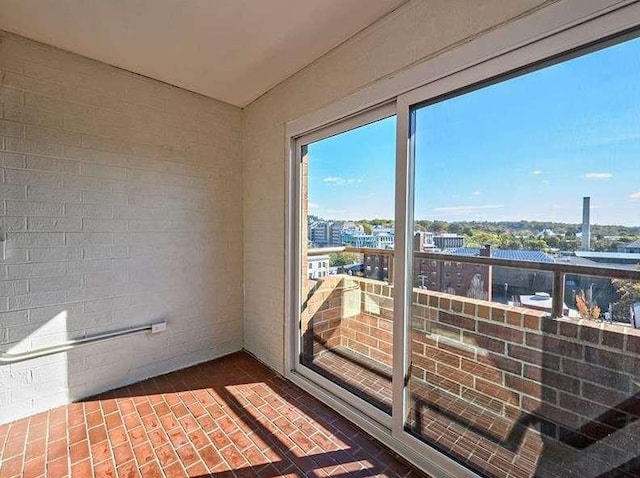 unfurnished sunroom with brick floor, a city view, and plenty of natural light