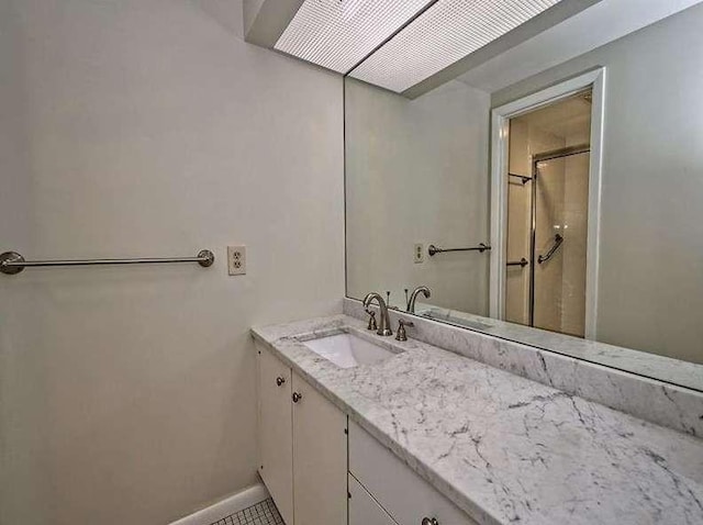 bathroom featuring walk in shower, vanity, and baseboards