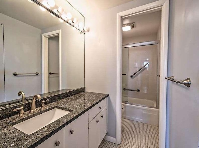 full bath featuring shower / bath combination with glass door, vanity, toilet, baseboards, and tile patterned flooring
