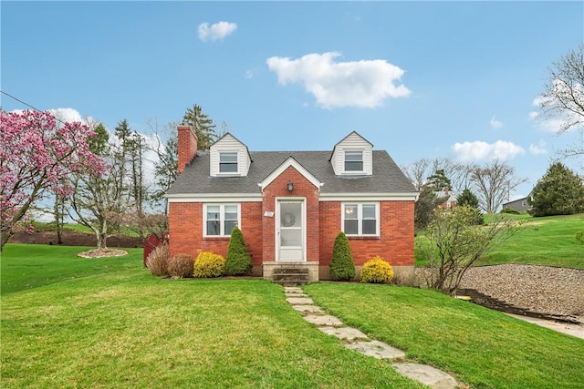 cape cod house featuring a shingled roof, a front lawn, and brick siding