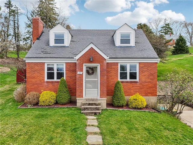 cape cod-style house featuring a chimney, a shingled roof, a front lawn, and brick siding
