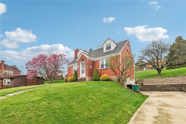 view of front of house with a front yard, brick siding, and a chimney