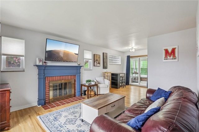 living room with a fireplace, baseboards, and wood finished floors