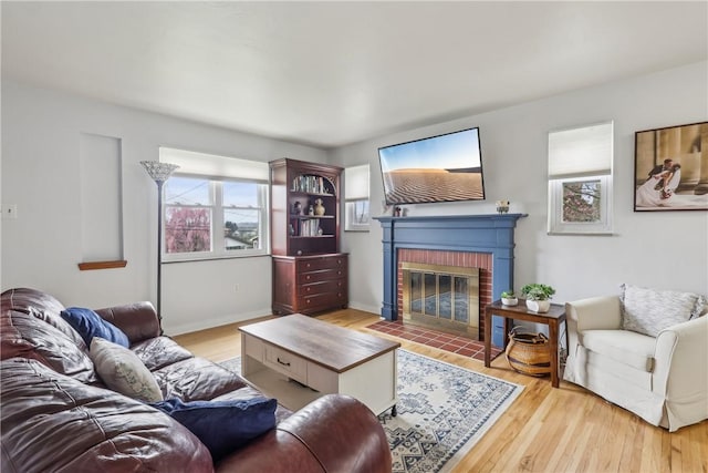 living area featuring wood finished floors, a brick fireplace, and plenty of natural light
