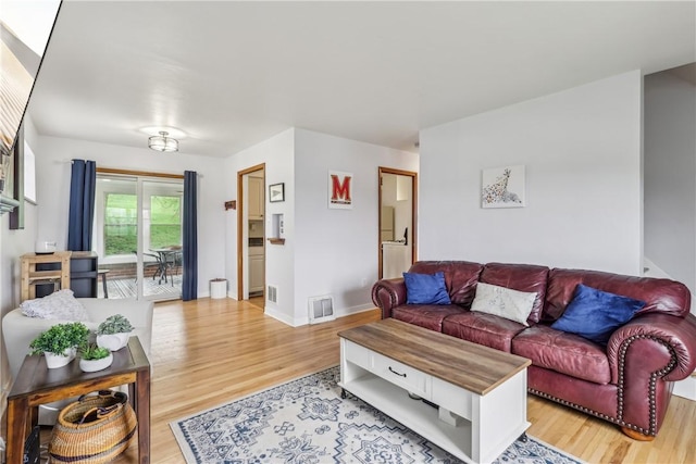 living room featuring light wood-style floors, baseboards, and visible vents