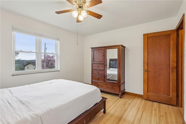 bedroom with baseboards, light wood finished floors, and ceiling fan