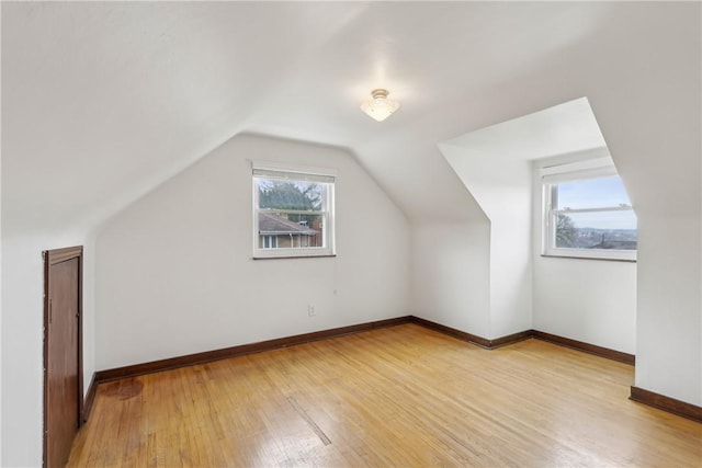 bonus room with light wood-style floors, baseboards, and lofted ceiling