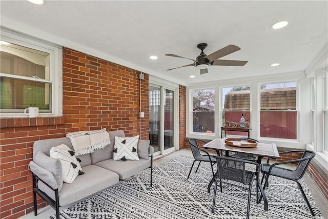 sunroom / solarium featuring outdoor lounge area, ceiling fan, outdoor dining area, and brick wall