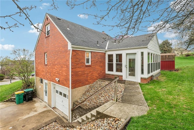 back of house featuring a yard, roof with shingles, brick siding, an attached garage, and driveway