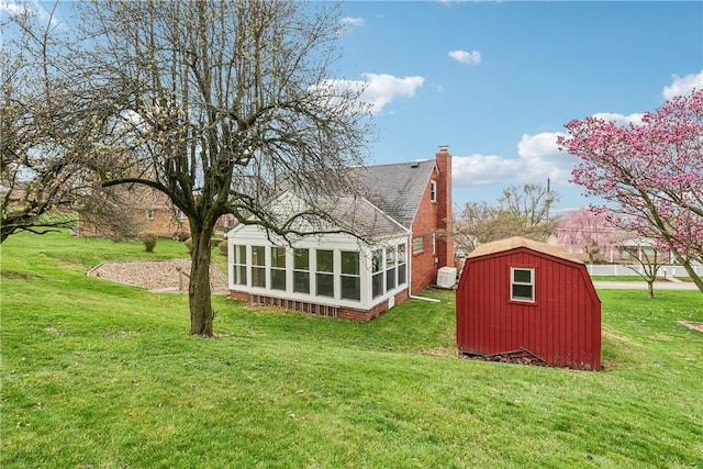 rear view of property with a sunroom, roof with shingles, a yard, and an outdoor structure
