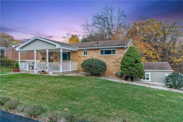 view of front of property with a porch, brick siding, and a yard