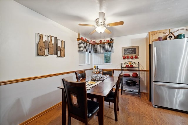 dining room with light wood-style flooring, a ceiling fan, and baseboards