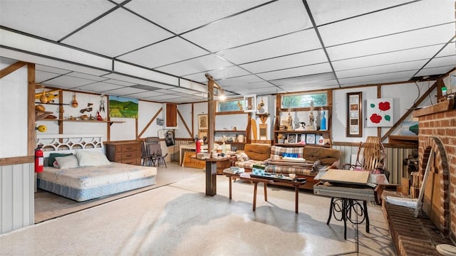 living room with tile patterned floors, a wainscoted wall, a paneled ceiling, and a brick fireplace