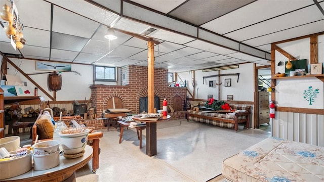 basement with a paneled ceiling, brick wall, tile patterned floors, a wood stove, and visible vents