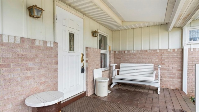 doorway to property featuring board and batten siding and brick siding