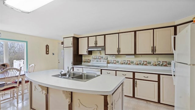 kitchen featuring white appliances, an island with sink, light countertops, under cabinet range hood, and a sink