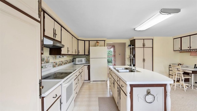 kitchen with white appliances, light countertops, under cabinet range hood, light floors, and a sink