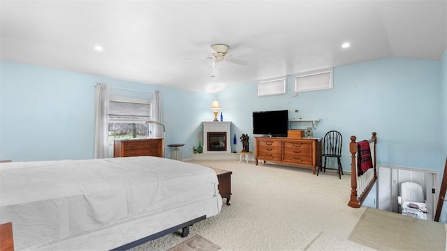 bedroom featuring a glass covered fireplace, vaulted ceiling, recessed lighting, ceiling fan, and carpet