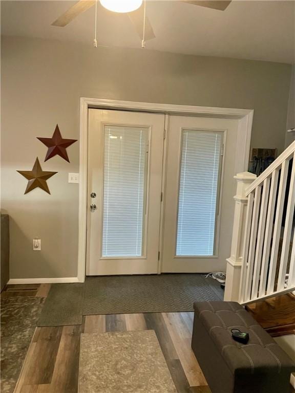 foyer entrance featuring wood finished floors, stairway, ceiling fan, and baseboards