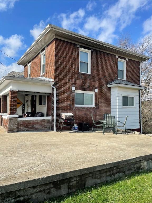 rear view of house featuring a patio and brick siding