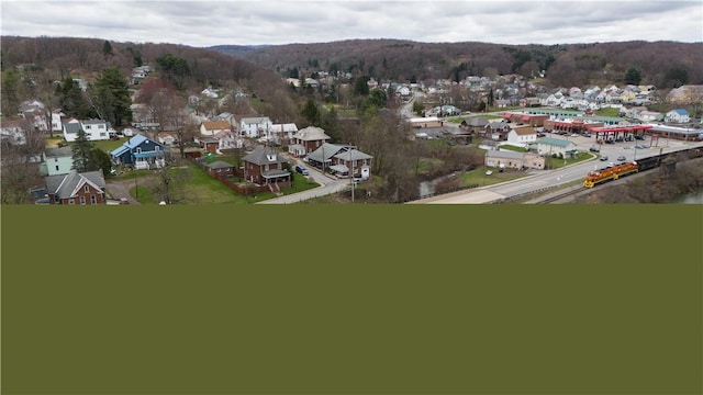 aerial overview of property's location featuring nearby suburban area and a heavily wooded area