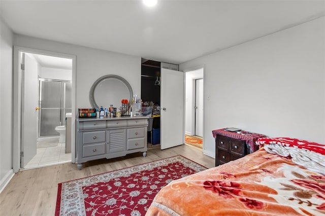 bedroom with light wood-type flooring and connected bathroom