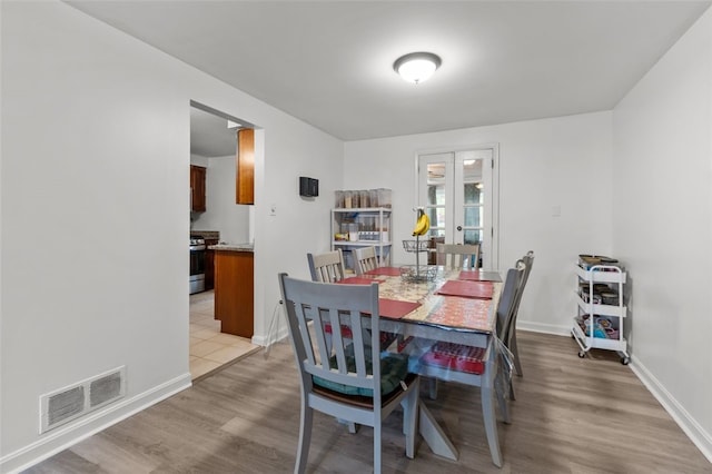 dining space featuring light wood-style floors, french doors, baseboards, and visible vents