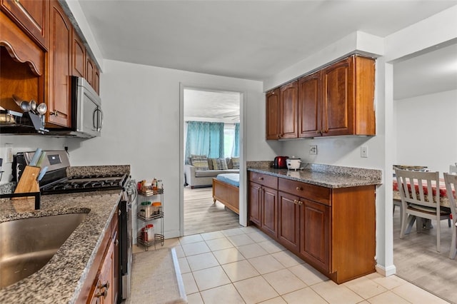 kitchen featuring dark stone countertops, light tile patterned floors, a sink, and stainless steel appliances
