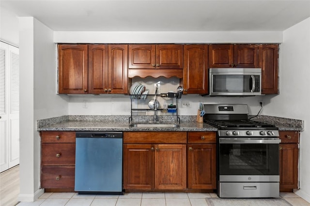 kitchen with a sink, appliances with stainless steel finishes, and dark stone counters